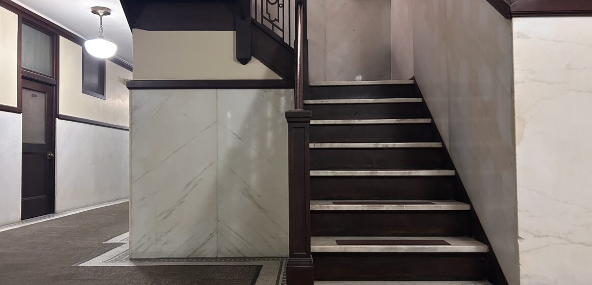Twohy Apartments brown stairway A brown and white stairway winds upwards.