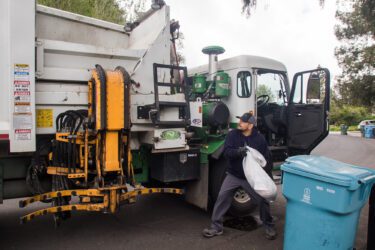 A man tosses trash into a garbage truck in Palo Alto, California