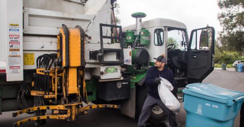 A man tosses trash into a garbage truck in Palo Alto, California