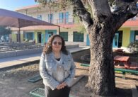A woman stands next to a tree outside a school in East San Jose, California