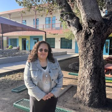 ESCUELA POPULAR A woman stands next to a tree outside a school in East San Jose, California