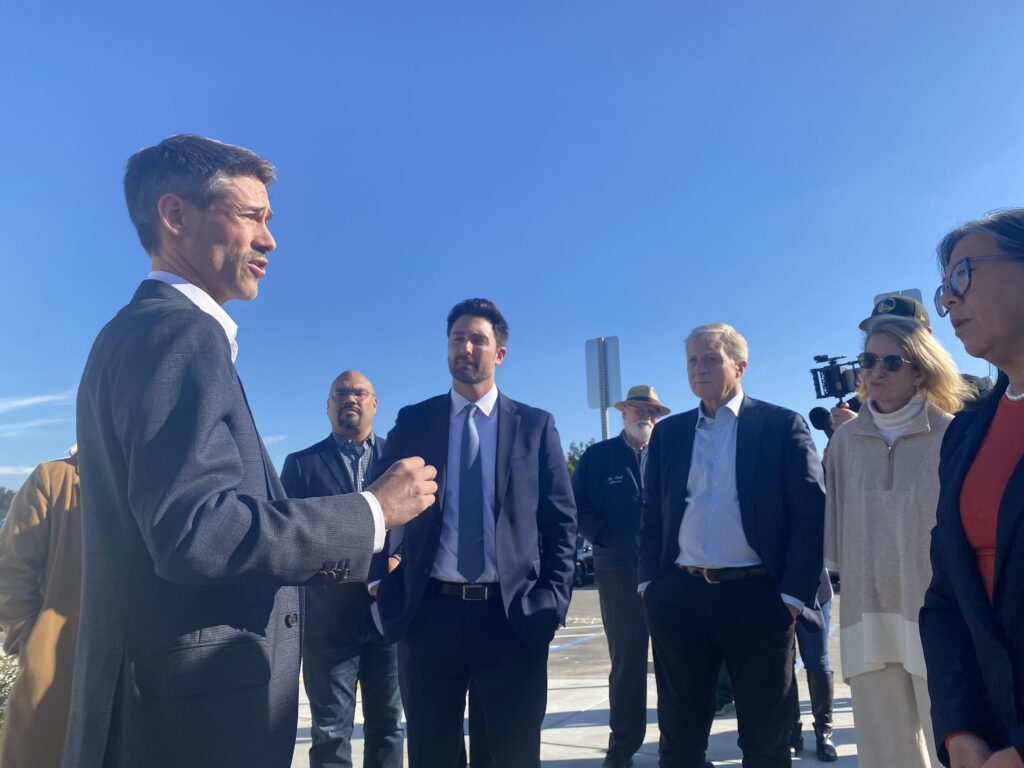 Un hombre con traje habla con personas en un complejo de viviendas para personas sin hogar en San José, California.