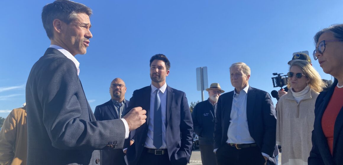 Gubernatorial tour Cherry Avenue San Jose A man in a suit speaks with people at a homeless housing site in San Jose, California