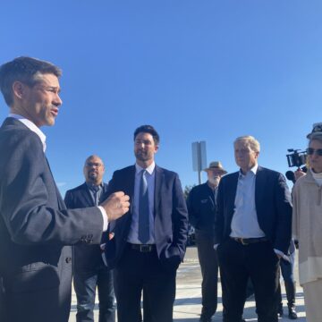 A man in a suit speaks with people at a homeless housing site in San Jose, California