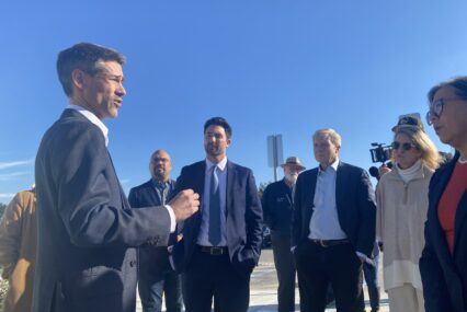 A man in a suit speaks with people at a homeless housing site in San Jose, California