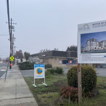940 Willow Street A sign on a grass field in front of a brown building next to a paved road.