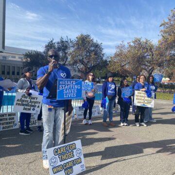 A group of nurses protesting and holding signs outside a hospital in San Jose, California