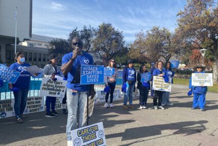 A group of nurses protesting and holding signs outside a hospital in San Jose, California