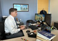 A man types on a keyboard at a desk in an office