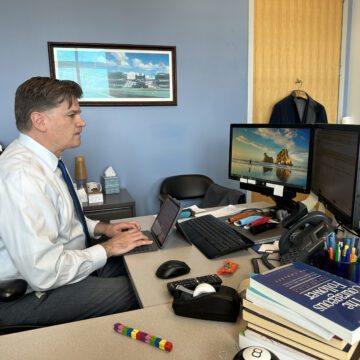 A man types on a keyboard at a desk in an office