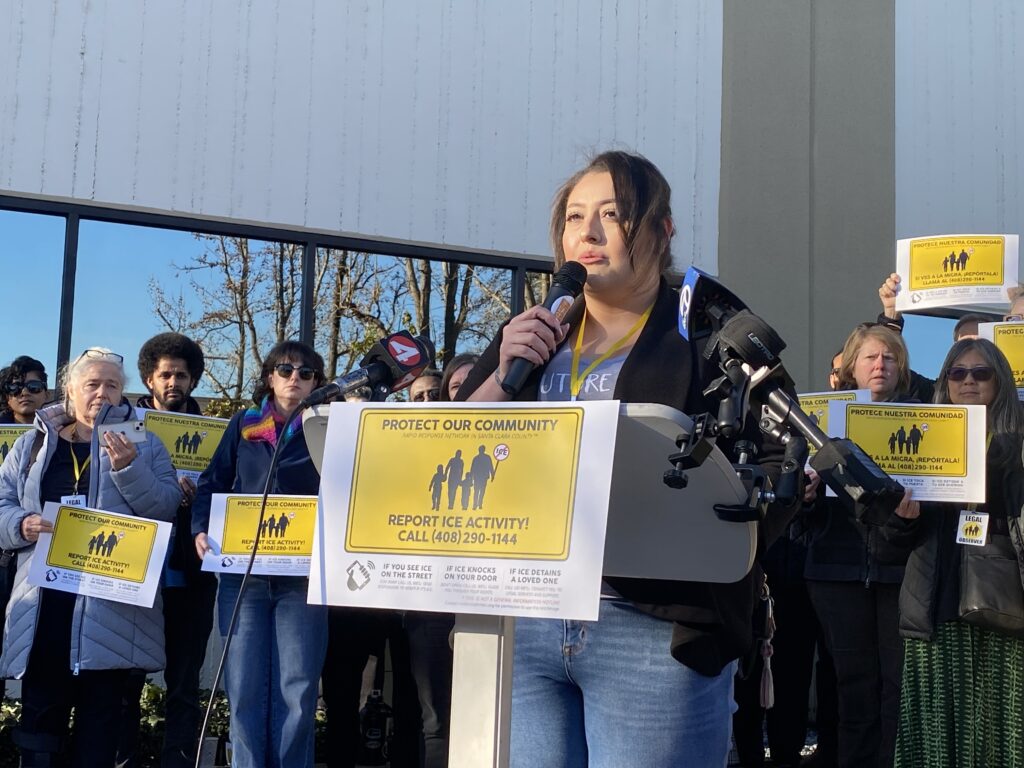 A woman speaks into a microphone at a podium in San Jose