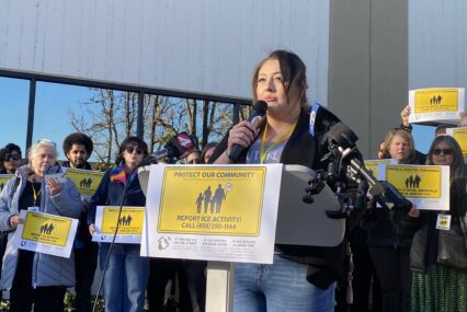 A woman speaks into a microphone at a podium in San Jose