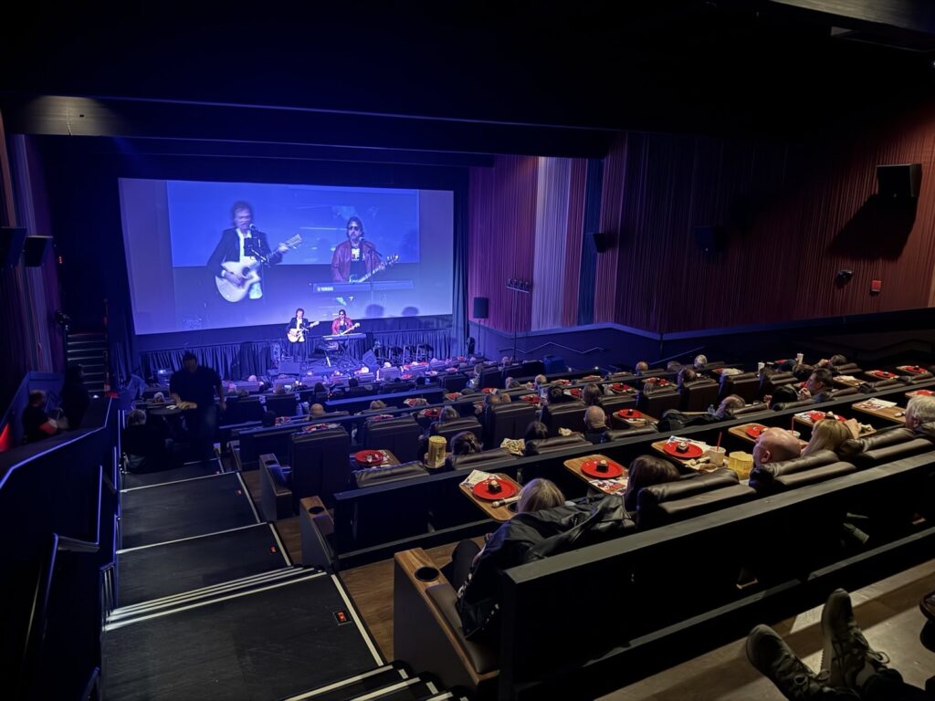 A theater with a concert and many people sitting in seats.