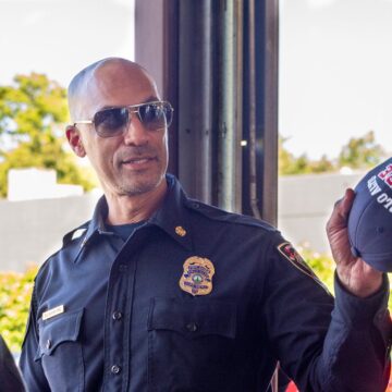 A firefighter wearing sunglasses and holding a hat in Palo Alto, California