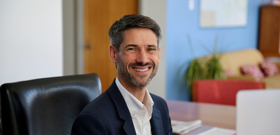 A man in a suit jacket sitting at a desk