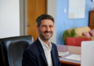 A man in a suit jacket sitting at a desk