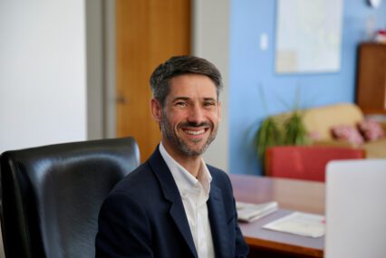 A man in a suit jacket sitting at a desk