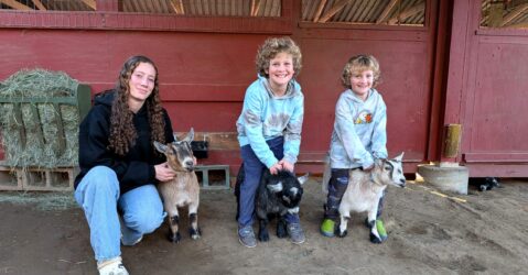 Three kids with their pet goats