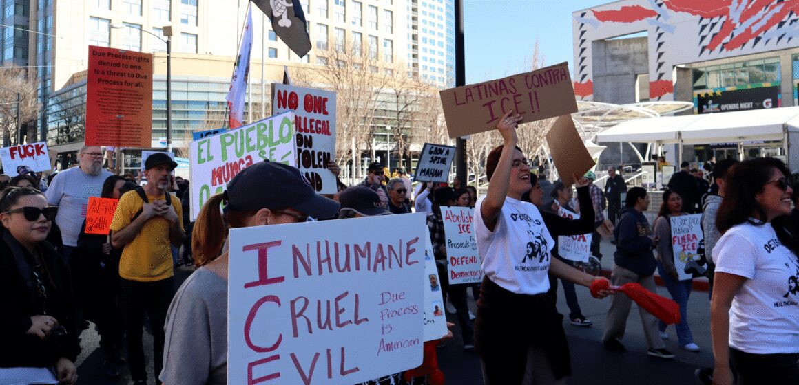 ICE Out Rally Photo of a group of people marching in front of the San Jose Convention Center, holding signs reading "INHUMANE CRUEL EVIL Due Process is American" and "LATINAS CONTRA ICE!!"