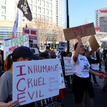 Photo of a group of people marching in front of the San Jose Convention Center, holding signs reading "INHUMANE CRUEL EVIL Due Process is American" and "LATINAS CONTRA ICE!!"