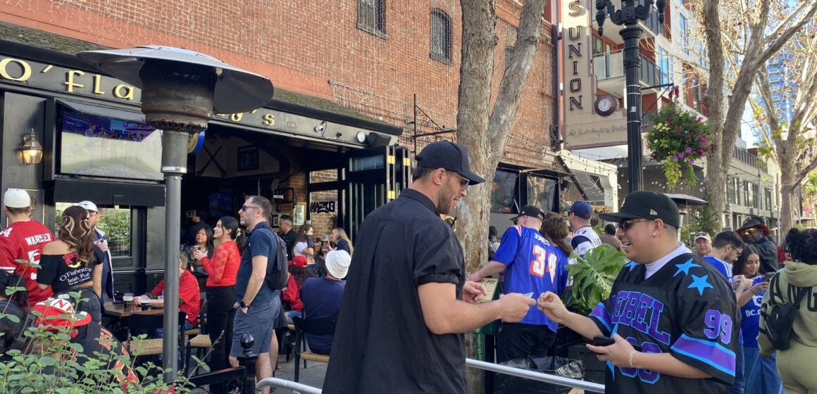 San Pedro crowds A man shows his ID to a bouncer to get into a bar. In the background, a large crowd is gathered.