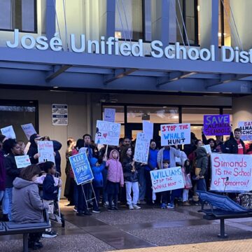 A group of people holding signs outside a school district office in San Jose, California