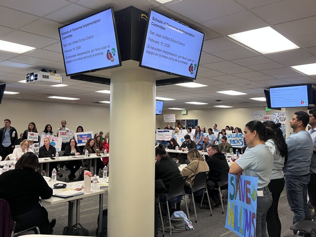 People holding signs at a school board meeting in San Jose, California