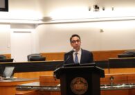 A man in a suit speaks at a podium at a government meeting in Santa Clara County, California