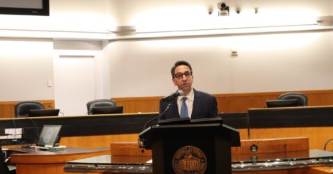 A man in a suit speaks at a podium at a government meeting in Santa Clara County, California