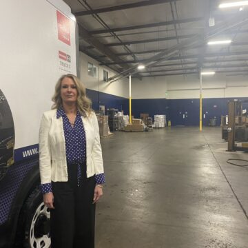 Nicole Guetersloh A woman in a white blazer stands in a warehouse.