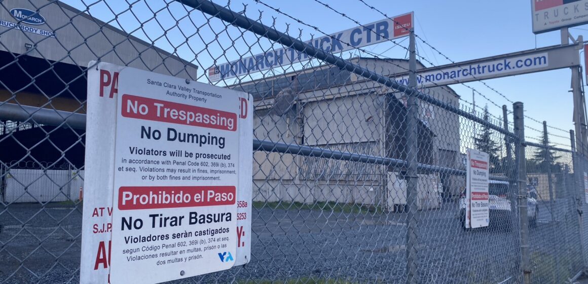 An industrial warehouse locked behind a chain fence.