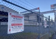 An industrial warehouse locked behind a chain fence.