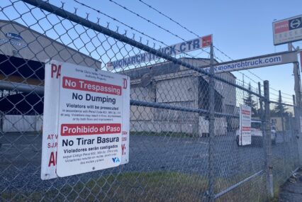 An industrial warehouse locked behind a chain fence.