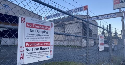 An industrial warehouse locked behind a chain fence.