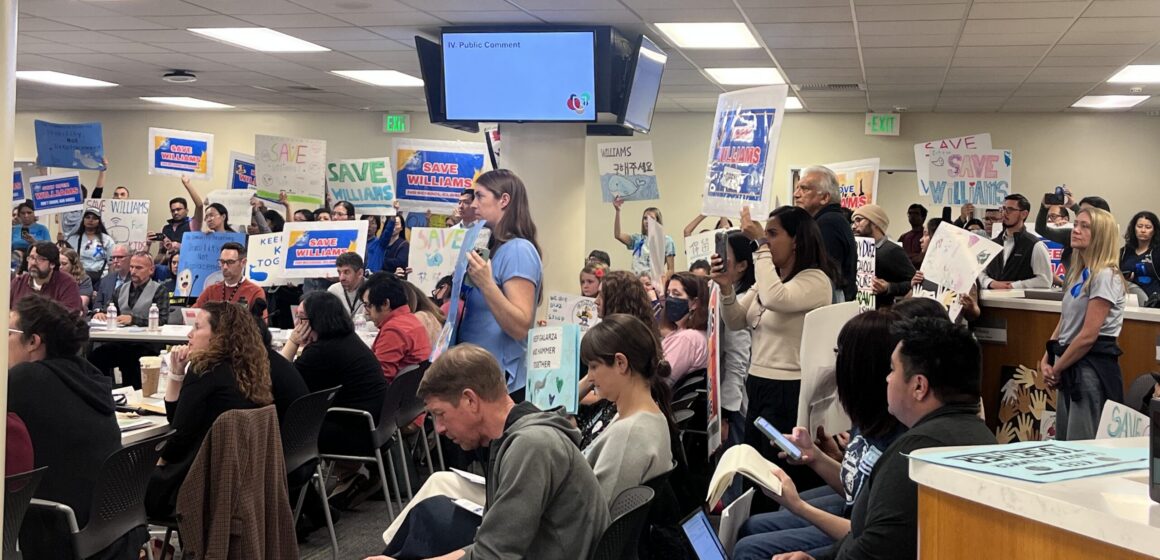 People holding up protest signs at a school board meeting in San Jose, California