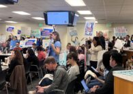 Personas sosteniendo carteles de protesta en una reunión de la junta escolar en San José, California.