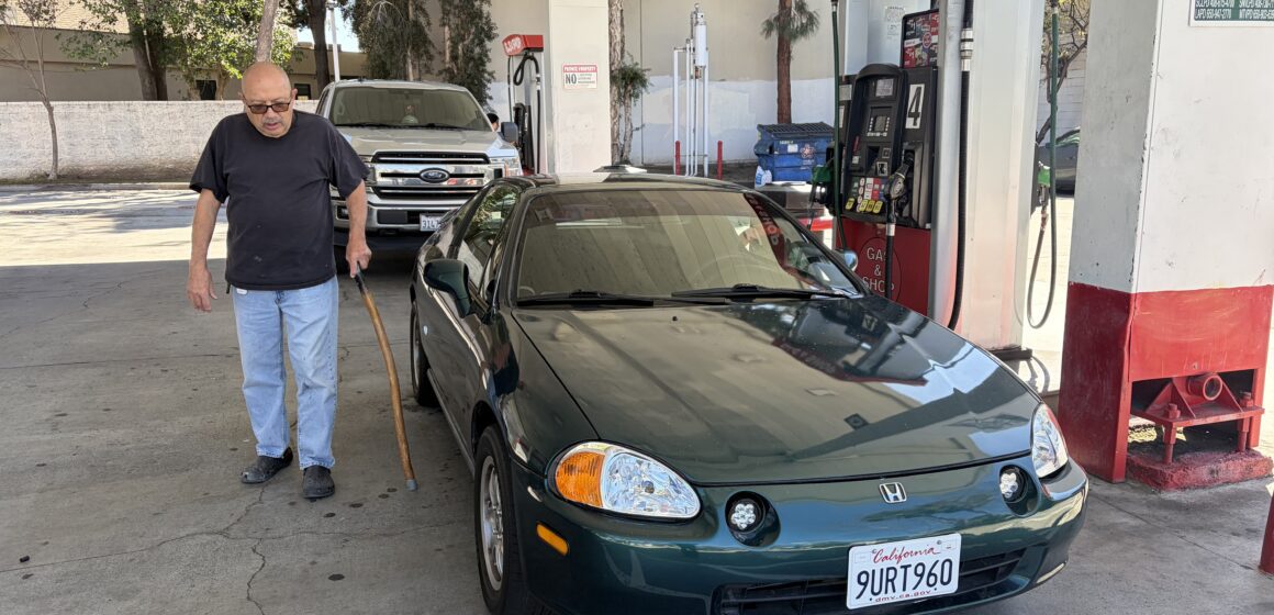 A man standing next to a car at a gas station in San Jose, California