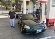 A man standing next to a car at a gas station in San Jose, California