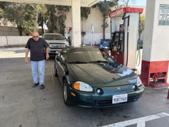 A man standing next to a car at a gas station in San Jose, California