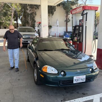 A man standing next to a car at a gas station in San Jose, California