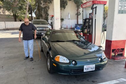 A man standing next to a car at a gas station in San Jose, California