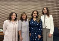 Four women standing in a line smiling at the viewer