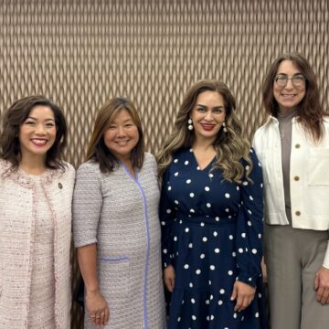 Four women standing in a line smiling at the viewer