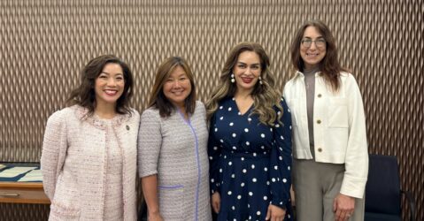 Four women standing in a line smiling at the viewer