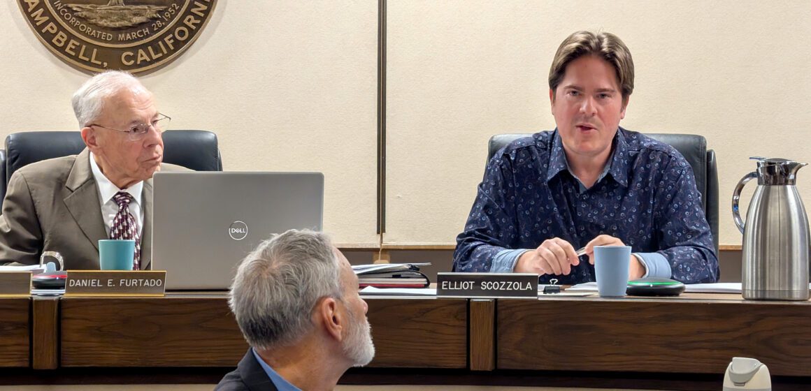Two men up on a dais at a government meeting, with another man in front of them in Campbell, California