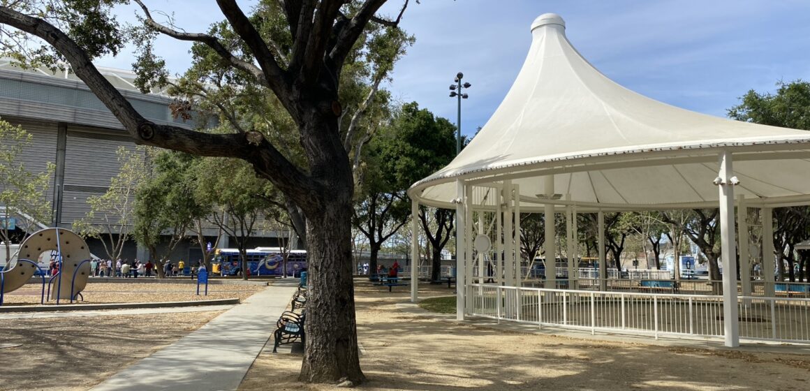 A tree stands in front of a white pavilion