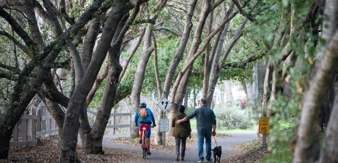 People walking on a trail near a creek in Mountain View, California