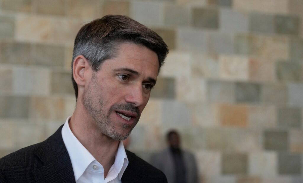 A man in a black suit jacket and white collared shirt
