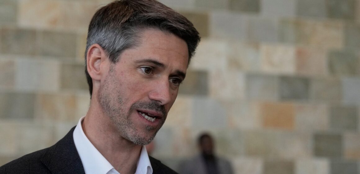 A man in a black suit jacket and white collared shirt