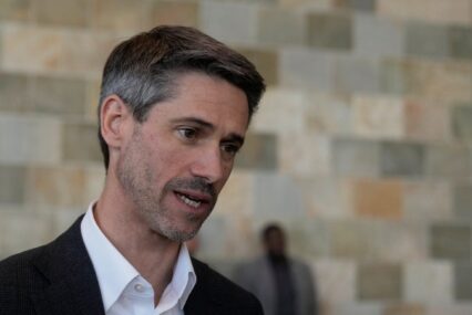 A man in a black suit jacket and white collared shirt